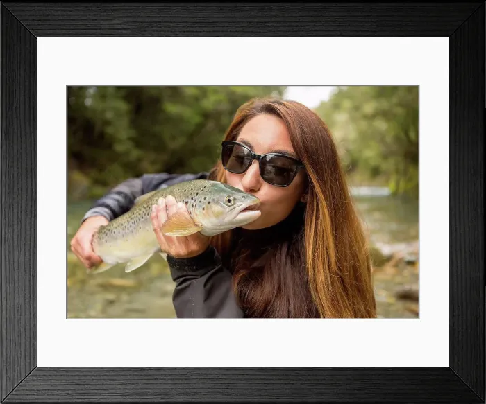 Framed Print : Caucasian woman kissing fish in remote river Framed Print : Caucasian woman kissing fish in remote river