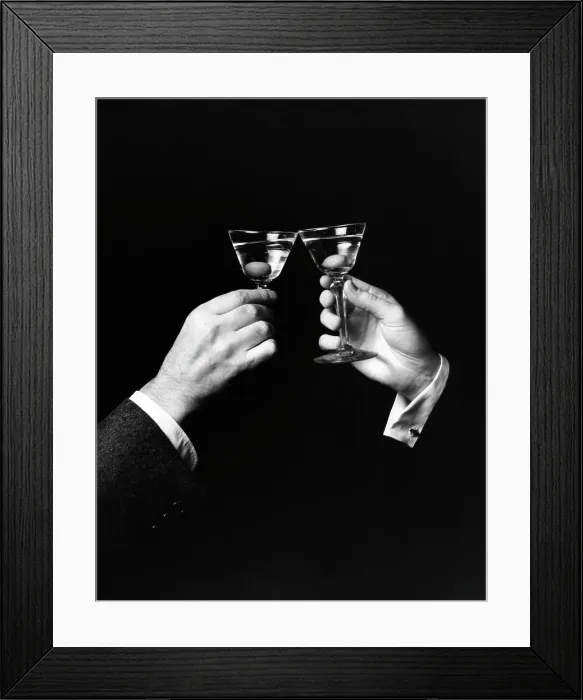 Framed Print : Two hands toasting with martini against black background Framed Print : Two hands toasting with martini against black background