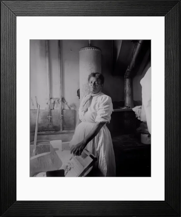 Framed Print : African American woman standing by a washtub with her hand on a washboard. Ca. 1920