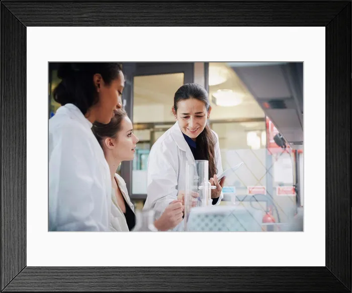 Framed Print : Smiling mature teacher with young female students learning chemistry at laboratory Framed Print : Smiling mature teacher with young female students learning chemistry at laboratory