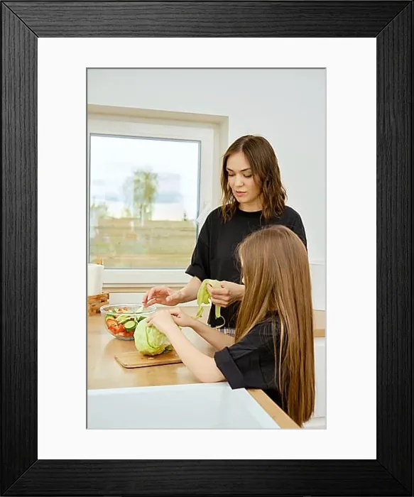 Framed Print : Mother and daughter tearing iceberg lettuce leaves into pieces while making food at home Framed Print : Mother and daughter tearing iceberg lettuce leaves into pieces while making food at home