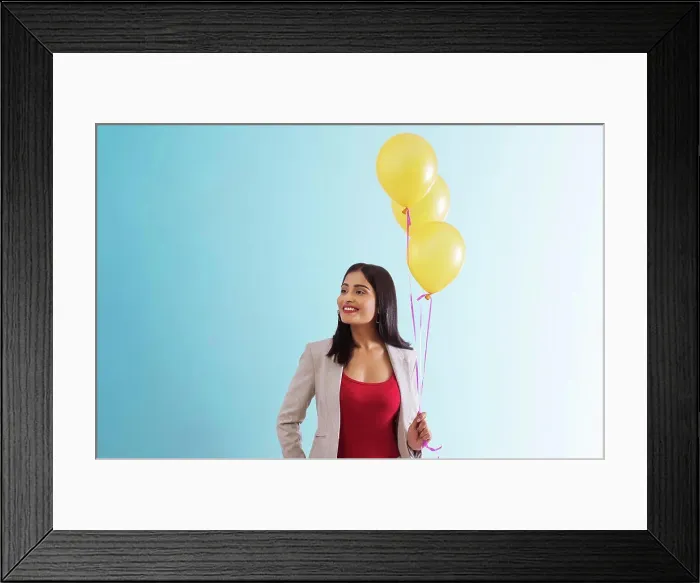 Framed Print : Young woman standing with helium balloons in hand Framed Print : Young woman standing with helium balloons in hand