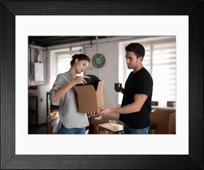Framed Print : Young couple unpacking plates during relocation Framed Print : Young couple unpacking plates during relocation