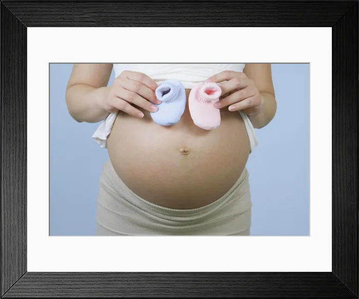Framed Print : Pregnant Chinese woman holding pink and blue booties Framed Print : Pregnant Chinese woman holding pink and blue booties