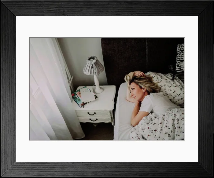 Framed Print : Woman lies in bed thoughtfully