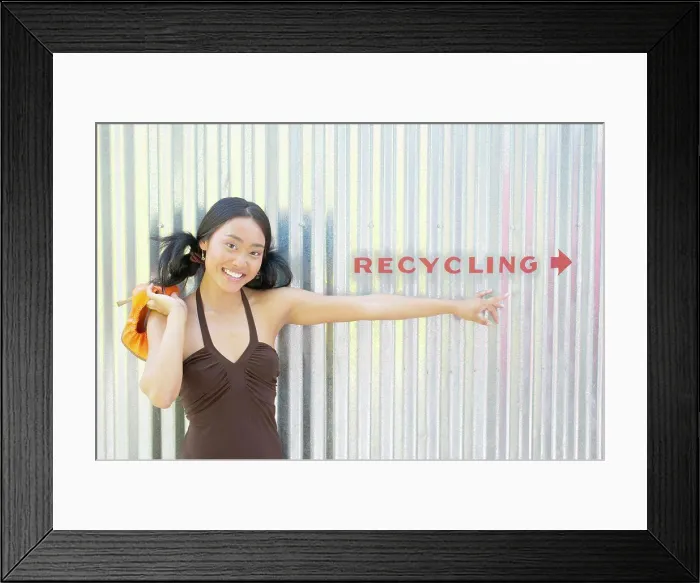 Framed Print : Portrait of a young woman standing against a corrugated metal wall smiling Framed Print : Portrait of a young woman standing against a corrugated metal wall smiling