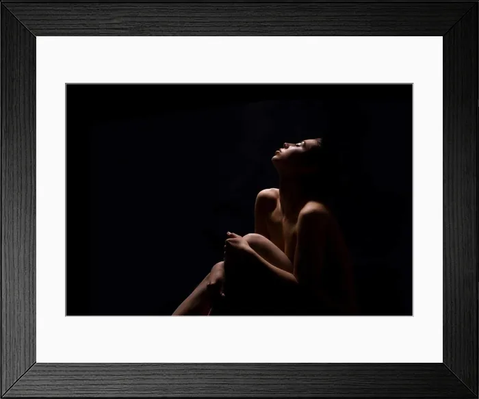 Framed Print : A woman sits with her knees drawn up to her chest, her head tilted back and her eyes closed, copy space Framed Print : A woman sits with her knees drawn up to her chest, her head tilted back and her eyes closed, copy space