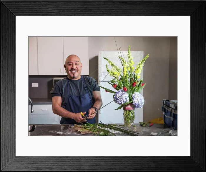 Framed Print : Smiling man arranging flowers in kitchen