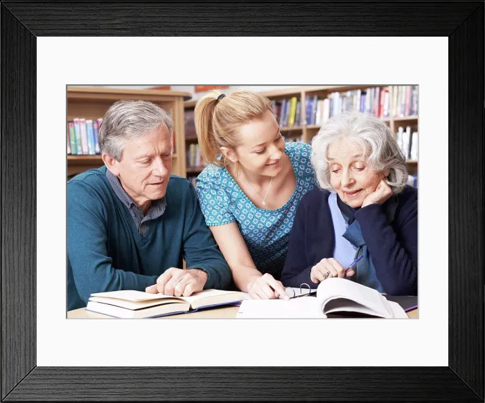 Framed Print : Mature Students Working With Teacher In Library Framed Print : Mature Students Working With Teacher In Library