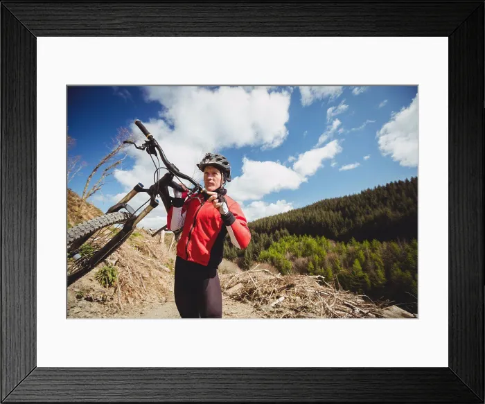 Framed Print : Biker carrying bicycle on mountain against sky