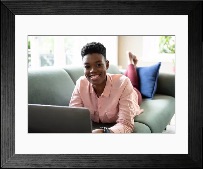 Framed Print : Portrait of african american woman lying on couch using laptop working from home Framed Print : Portrait of african american woman lying on couch using laptop working from home