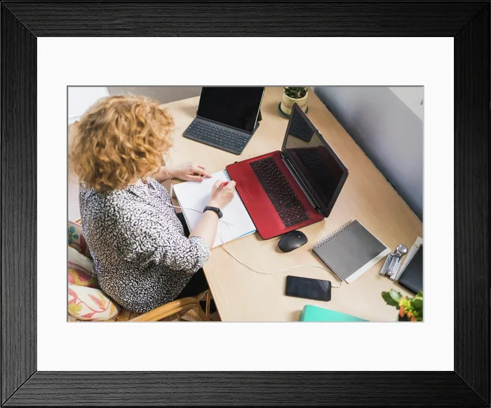 Framed Print : From above view of anonymous female freelancer taking notes with pen in notebook while listening music in earphones Framed Print : From above view of anonymous female freelancer taking notes with pen in notebook while listening music in earphones