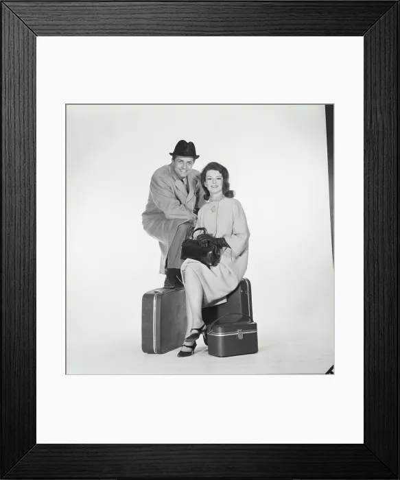 Framed Print : Portrait of a mid adult couple sitting with luggage Framed Print : Portrait of a mid adult couple sitting with luggage