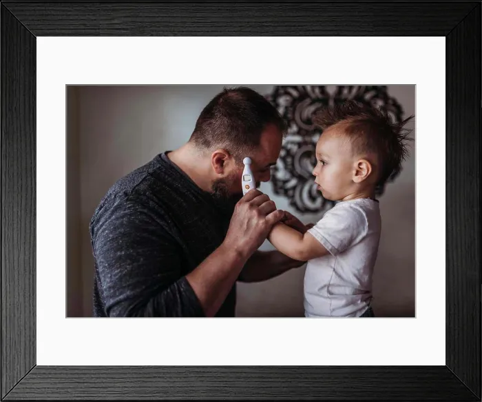 Framed Print : One year old boy taking father's temperature at home during isolation Framed Print : One year old boy taking father's temperature at home during isolation