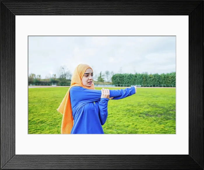 Framed Print : Ethnic female athlete stretching arms before running training