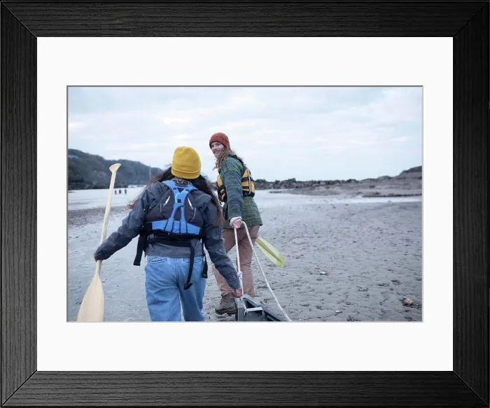 Framed Print : Young couple with oars pulling canoe on beach Framed Print : Young couple with oars pulling canoe on beach