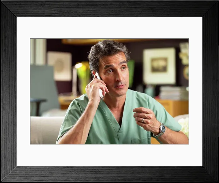 Framed Print : Hispanic Male doctor practicing tele-medicine from his home office, Talking to patient on cell phone