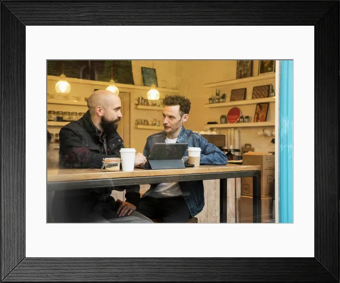 Framed Print : Friends sitting in window of cafe with tablet Framed Print : Friends sitting in window of cafe with tablet