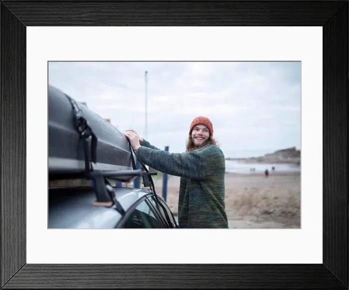 Framed Print : Smiling young man fastening canoe onto car at beach Framed Print : Smiling young man fastening canoe onto car at beach