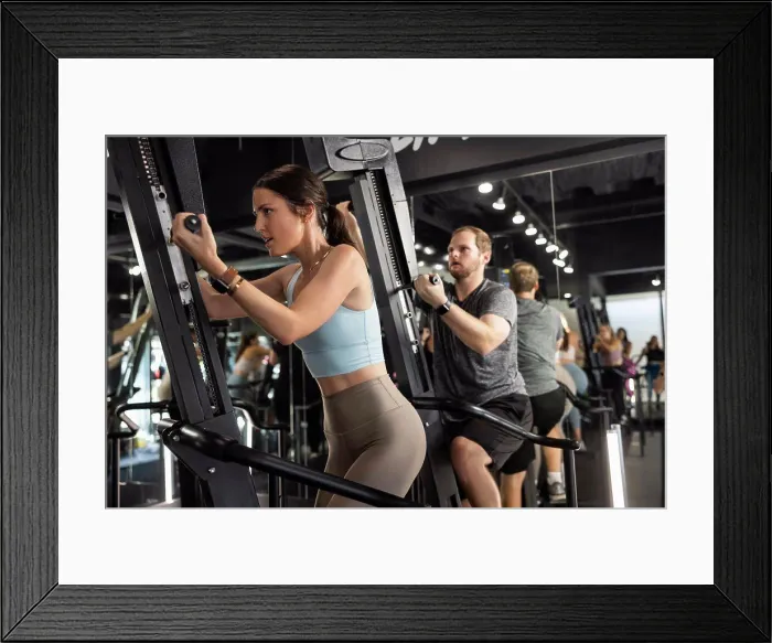 Framed Print : Woman training in gym on an exercise machine in group Framed Print : Woman training in gym on an exercise machine in group
