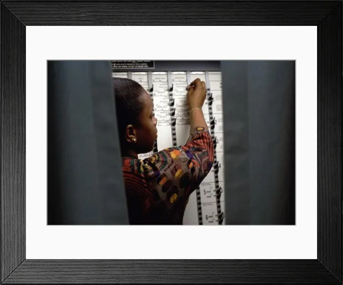 Framed Print : Rear view of a young woman voting in a voting booth