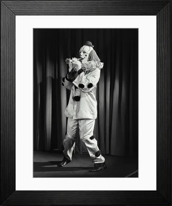 Framed Print : Vintage photograph. Portrait of clown wearing silly hat and playing toy horn