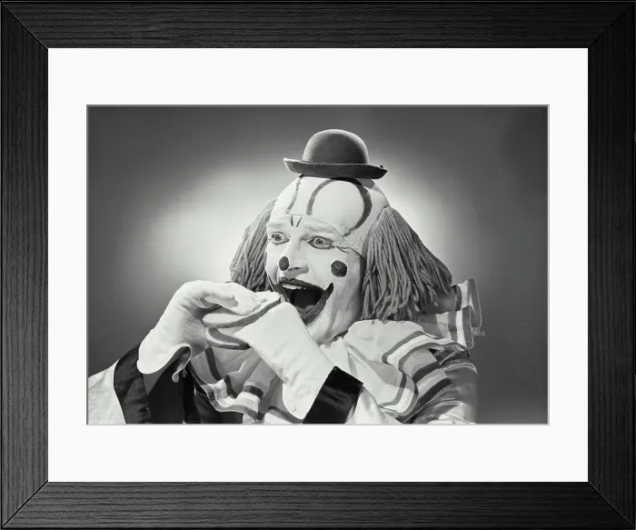 Framed Print : Vintage photograph. Portrait of clown wearing silly hat with hand sandwiched between two pieces of bread