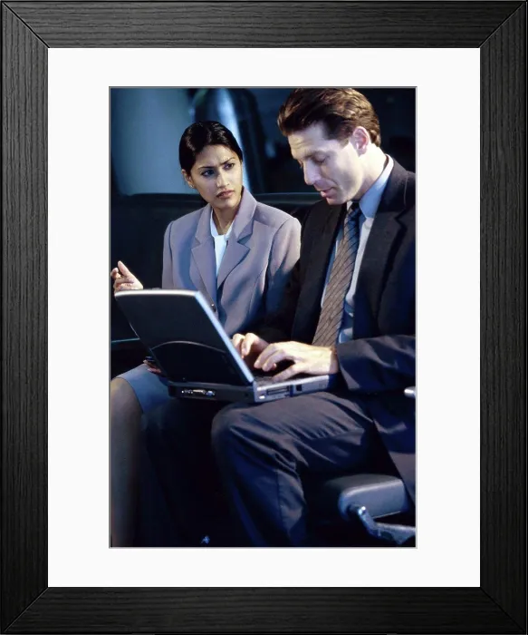 Framed Print : Side profile of a businessman and businesswoman sitting in front of a laptop