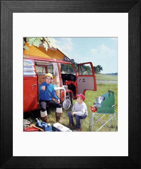 Framed Print : 1970s MAN AND BOY CAMPING SON SITTING BY PORTABLE STOVE FATHER SITTING BY CAMPER WITH FISHING RODS AND GEAR