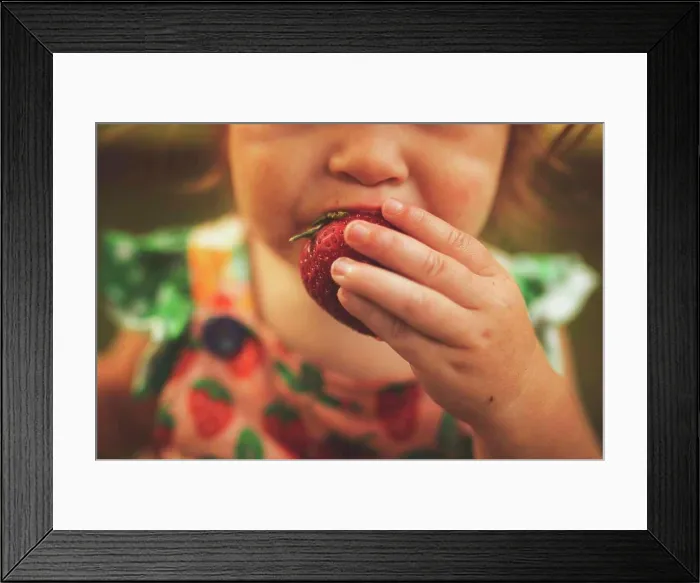 Framed Print : Girl eating strawberries in summer Framed Print : Girl eating strawberries in summer