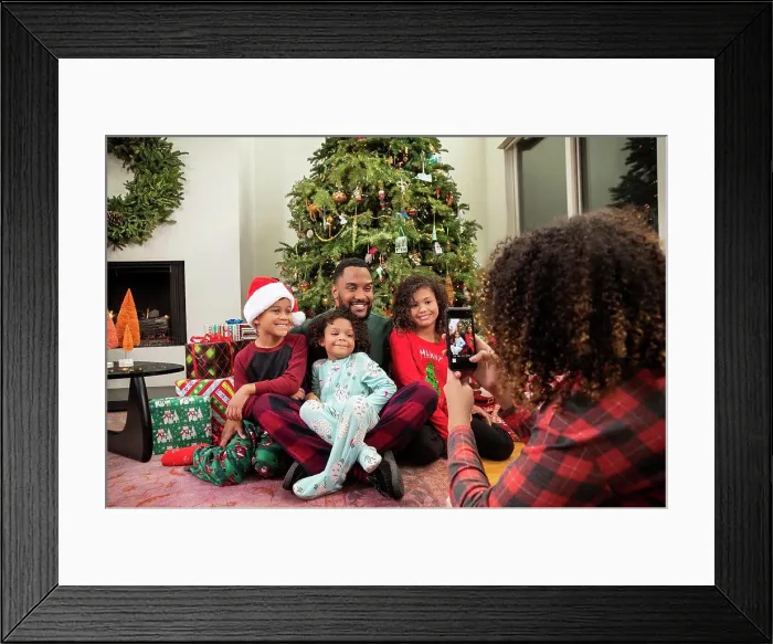 Framed Print : Young Black family taking pictures on mobile phone under Christmas tree