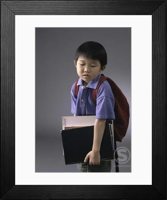 Framed Print : Portrait of a boy carrying book and a backpack Framed Print : Portrait of a boy carrying book and a backpack