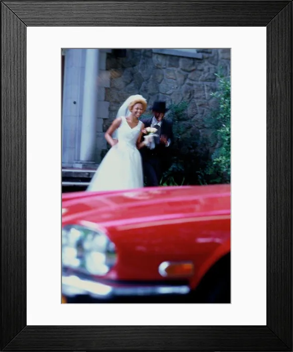 Framed Print : Newlywed couple running towards a car Framed Print : Newlywed couple running towards a car