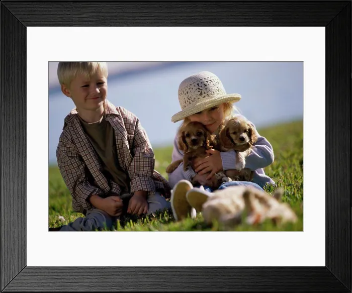 Framed Print : Boy and a girl sitting with puppies Framed Print : Boy and a girl sitting with puppies