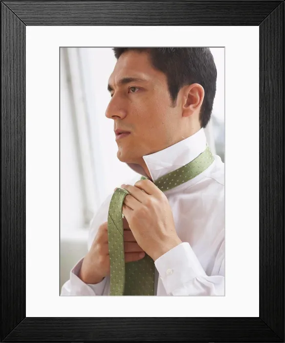 Framed Print : Side profile of a businessman tying his tie Framed Print : Side profile of a businessman tying his tie