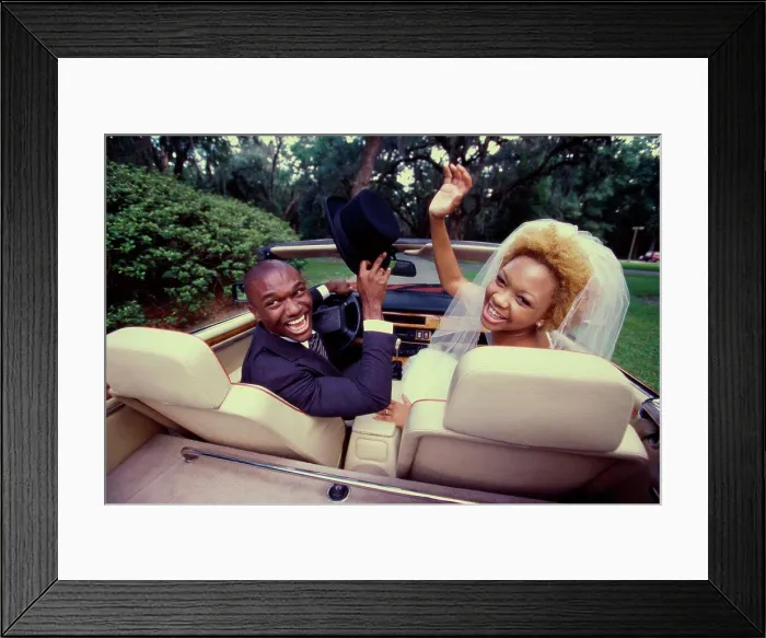 Framed Print : Rear view of a newlywed couple sitting in a convertible car