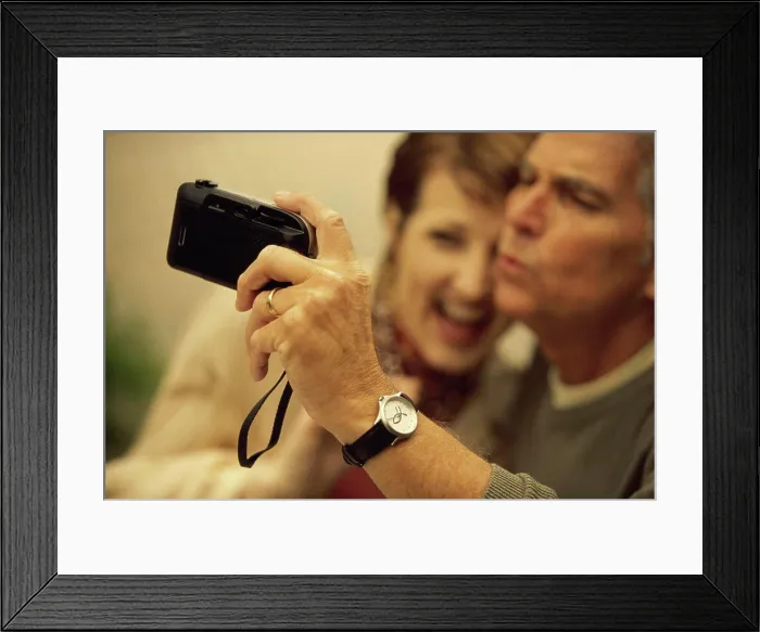 Framed Print : Mid adult couple taking a photograph of themselves Framed Print : Mid adult couple taking a photograph of themselves