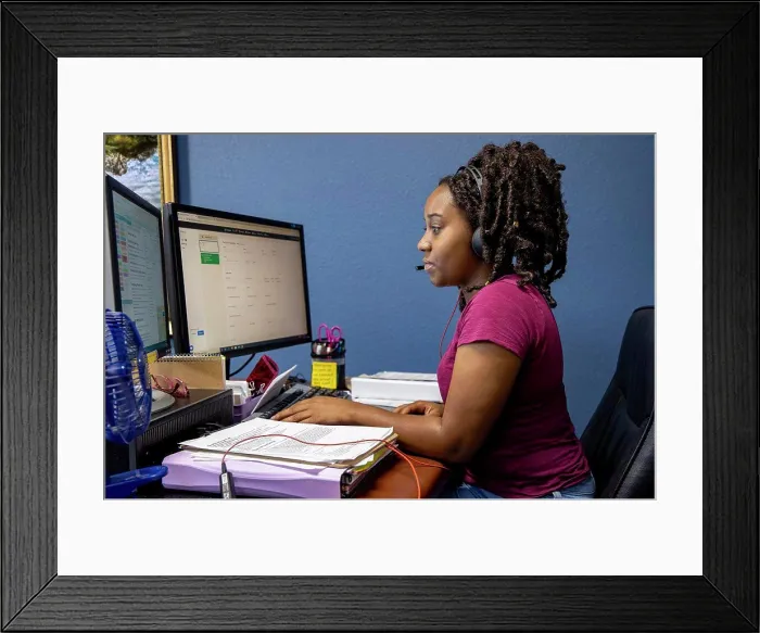 Framed Print : A portrait of an African American woman at her call center desk and her headset on, working from home Framed Print : A portrait of an African American woman at her call center desk and her headset on, working from home