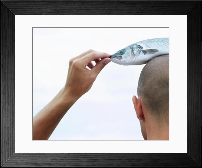 Framed Print : Rear view of a young man with a dead fish on his head Framed Print : Rear view of a young man with a dead fish on his head