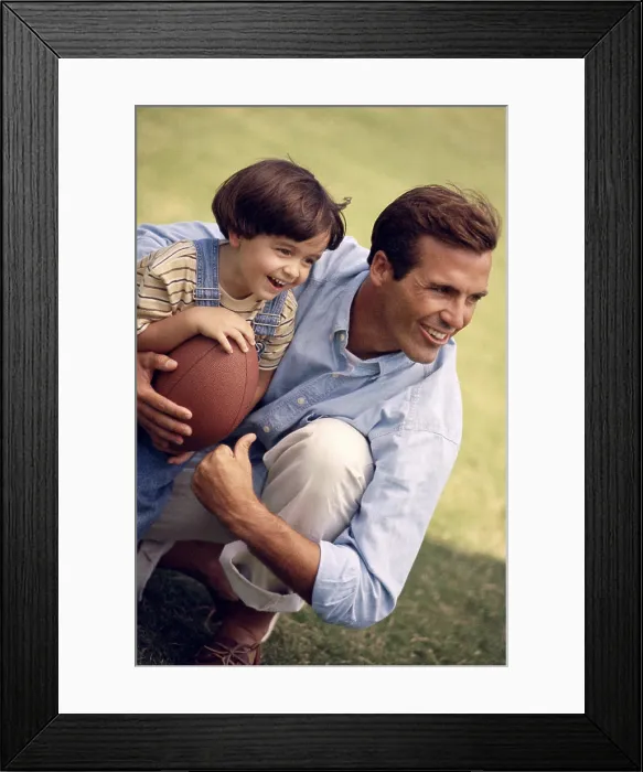 Framed Print : Father holding his daughter and a football