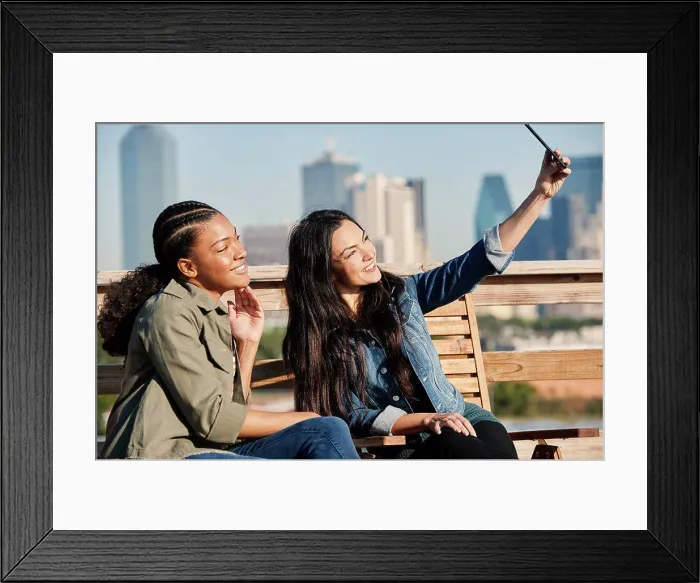 Framed Print : Group of young co-workers hanging out on rooftop patio, two women taking selfie with mobile phone Framed Print : Group of young co-workers hanging out on rooftop patio, two women taking selfie with mobile phone