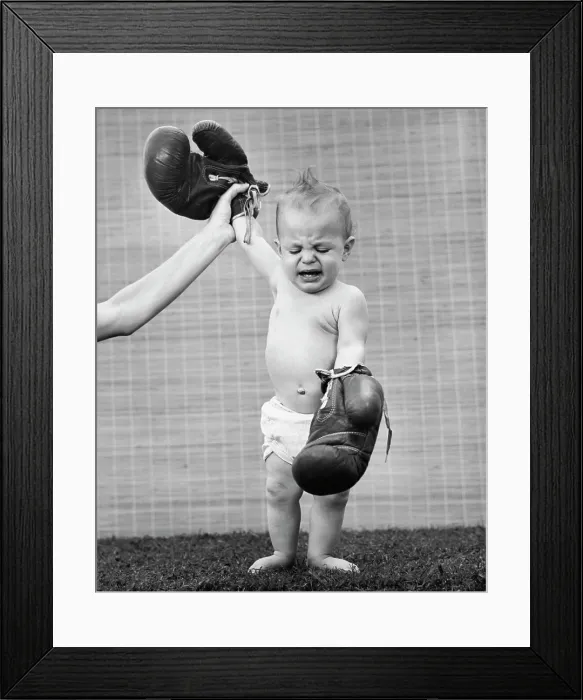 Framed Print : Person's hand raising a baby's hand wearing boxing gloves Framed Print : Person's hand raising a baby's hand wearing boxing gloves