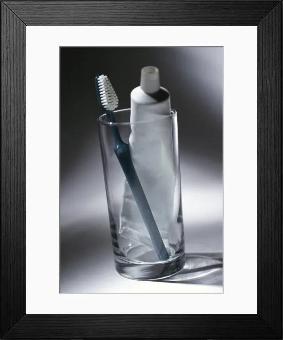 Framed Print : Toothbrush and a tube of toothpaste in a glass