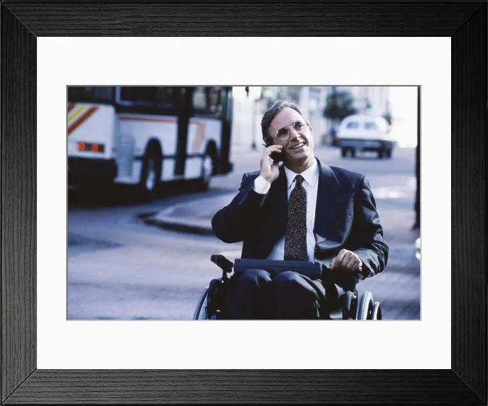 Framed Print : Close-up of a businessman in a wheelchair talking on a mobile phone Framed Print : Close-up of a businessman in a wheelchair talking on a mobile phone