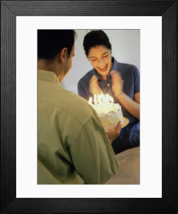 Framed Print : Mid adult man holding a birthday cake in front of a mid adult woman Framed Print : Mid adult man holding a birthday cake in front of a mid adult woman
