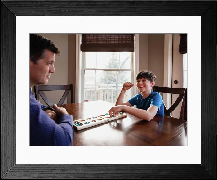 Framed Print : Boy and his father having fun playing a game together at home Framed Print : Boy and his father having fun playing a game together at home