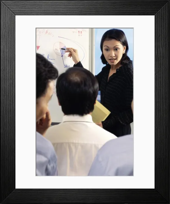 Framed Print : Businesswoman pointing to a pie chart on a whiteboard