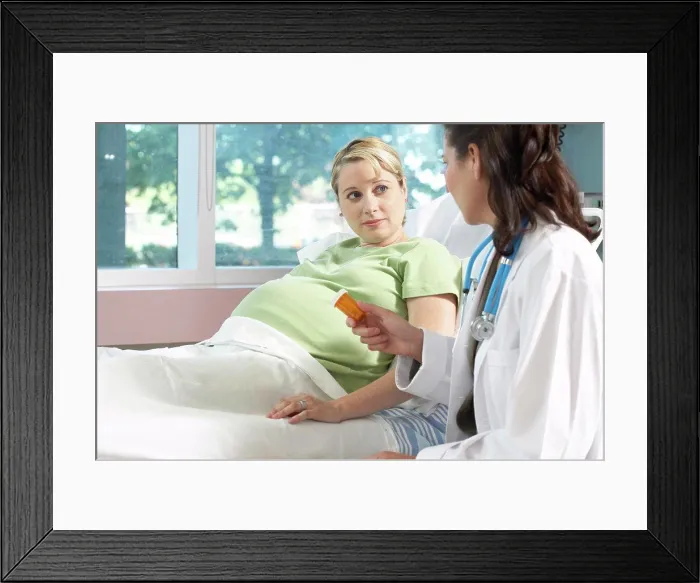 Framed Print : Side profile of a female doctor giving a bottle of pills to a pregnant woman Framed Print : Side profile of a female doctor giving a bottle of pills to a pregnant woman