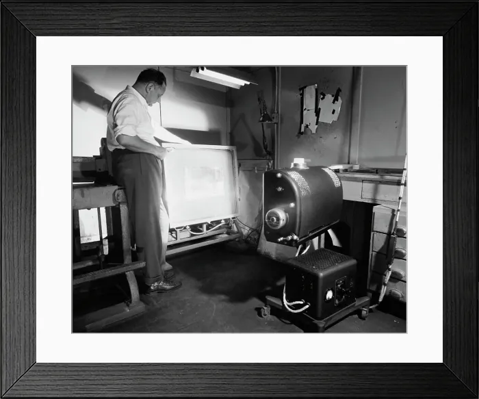 Framed Print : Side profile of a male worker operating a photoengraving camera Framed Print : Side profile of a male worker operating a photoengraving camera