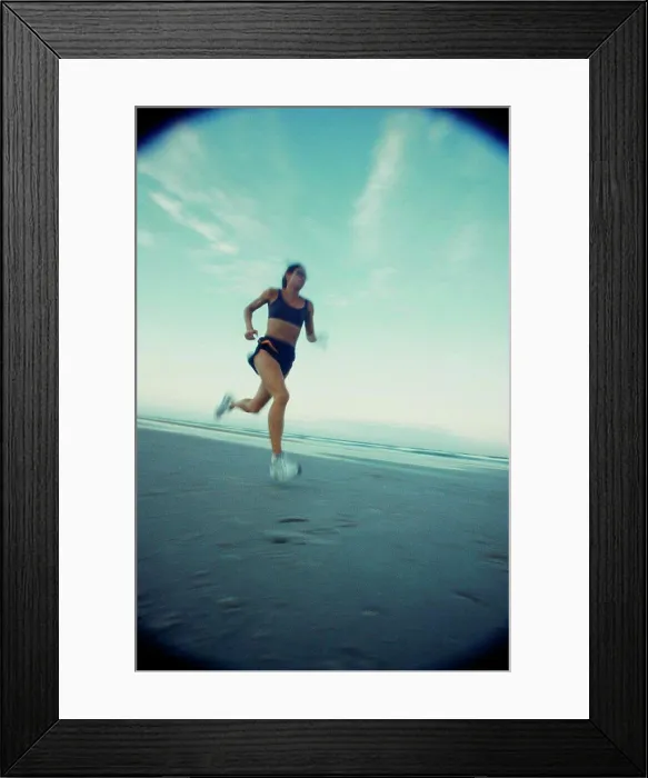 Framed Print : Low angle view of a young woman running on the beach